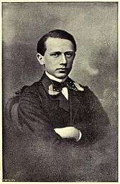 A clean-shaven man in his teens wearing a dress shirt, tie and dark uniform jacket.