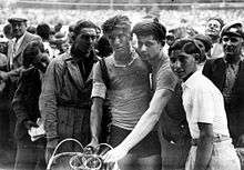 Five persons posing while holding one bicycle