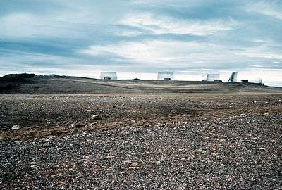 A series of four metal structures silhouetted on the horizon, with a golf ball looking dome to the left