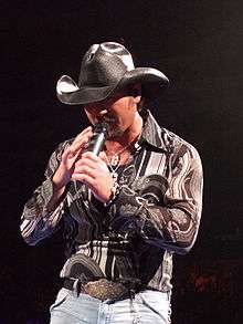 A man in a cowboy hat singing into a microphone