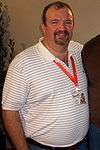 Half-length view of a large, balding, Caucasian man in a striped shirt.