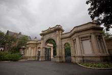 Arched gate with a small lodge to right and left.