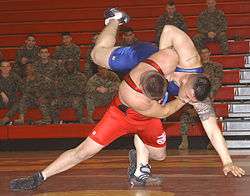 Two wrestlers, one wearing red and the other blue