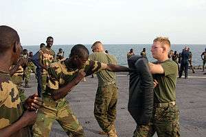 US Navy 051103-M-2175L-200 U.S. Marine Corps Lance Cpl. Ryan Papa, right, assigned to 2nd Platoon, Company C, 1st Battalion, 8th Marine Regiment, holds a striking pad for a member of the Senegalese 90th Naval Infantry.