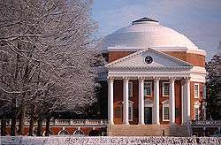 A red brick, Neoclassical dome with a large portico on the front and covered walkway on the sides. Snow covers the foreground and trees.