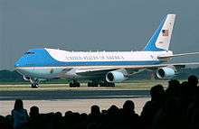 Presidential aircraft taxiing in front of silhouetted crowd.