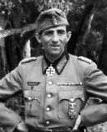 A man wearing a military uniform with an Iron Cross displayed at the front of his uniform collar.