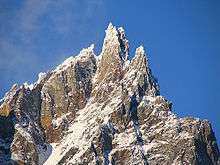 Tall rugged mountain lightly covered with snow.