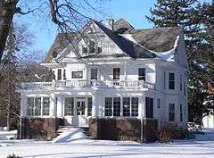 Large two-story cross-gabled house in snow