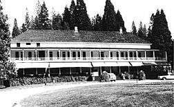 Historic photograph of the Wawona Hotel, a broad, two-story building with trees in the background.