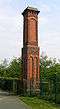 A chimney-like brick structure in two stages with some brick decoration and a corbelled top