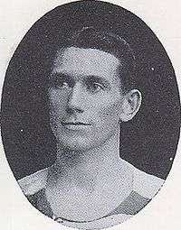 A black and white photograph of a head shot of a Caucasian man with hair slicked to the side.