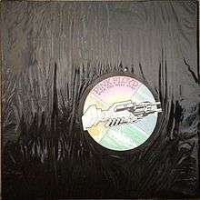 The black plastic covers the whole vinyl package. The circle sticker at the right-center position shows two machines clasped together, resembling a handshake. The whole circle is divided into four quarters in different colors. The pink quarter, located on north, has "PINK FLOYD" in big font; below the band name is "WISH YOU WERE HERE" in small font. The yellow quarter is at west; the blue quarter, east; the green quarter, south.