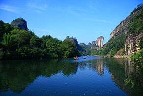 A river lined by dense vegetation and steep rocks.